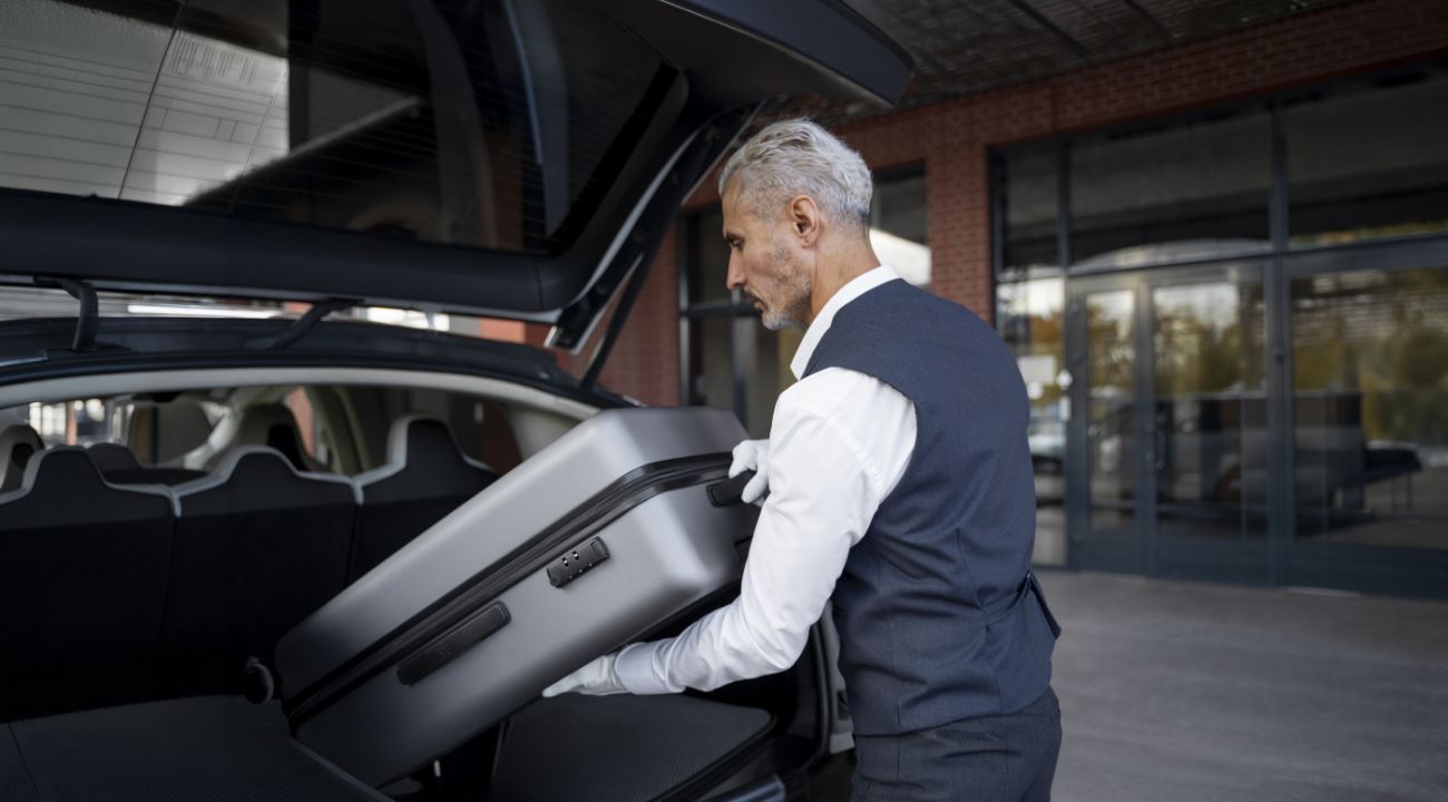 Conductor profesional guardando equipaje en vehículo premium Conductor de servicio de transfers preparando maletero de vehículo de lujo para viajero con equipaje